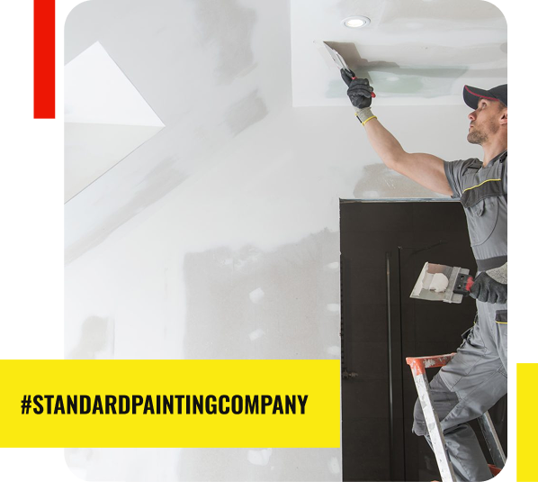 A painter standing on a ladder smooths a white ceiling with a trowel in a room under renovation. Text on a yellow banner reads #STANDARDPAINTINGCOMPANY, your trusted painting contractor for top Painting Services in Park Ridge.